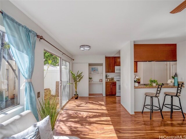 kitchen with a kitchen bar, white appliances, kitchen peninsula, and light wood-type flooring