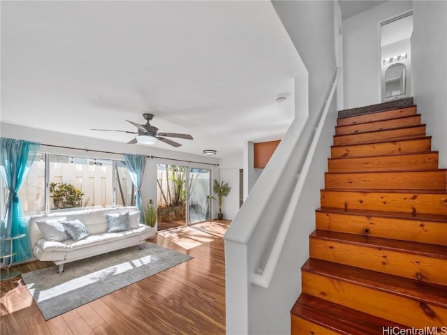 staircase with a ceiling fan and wood finished floors