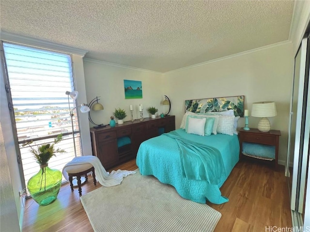 bedroom with a textured ceiling, crown molding, and wood-type flooring