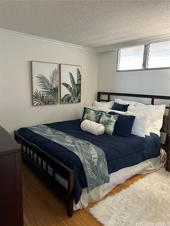 bedroom featuring a textured ceiling, hardwood / wood-style floors, and crown molding