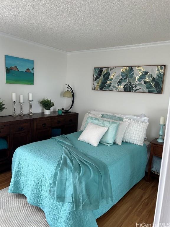 bedroom featuring a textured ceiling, ornamental molding, and hardwood / wood-style floors