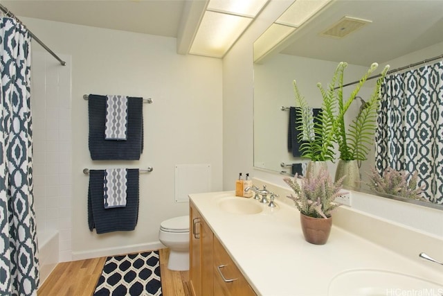 full bathroom featuring hardwood / wood-style floors, vanity, shower / tub combo with curtain, and toilet