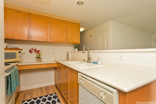 kitchen with kitchen peninsula, sink, light hardwood / wood-style floors, and white appliances