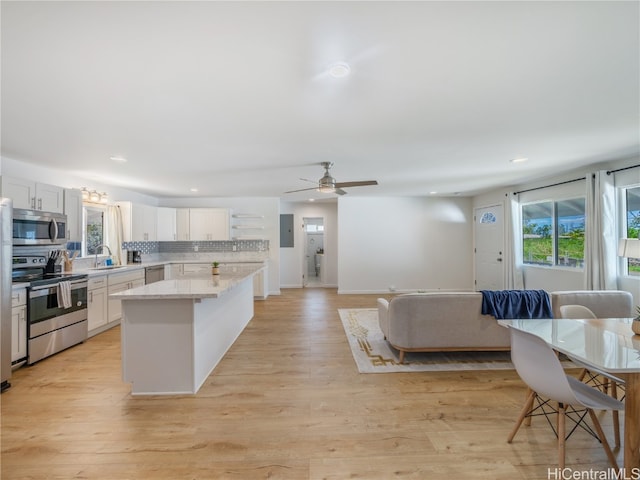 kitchen with appliances with stainless steel finishes, open floor plan, white cabinets, and a sink