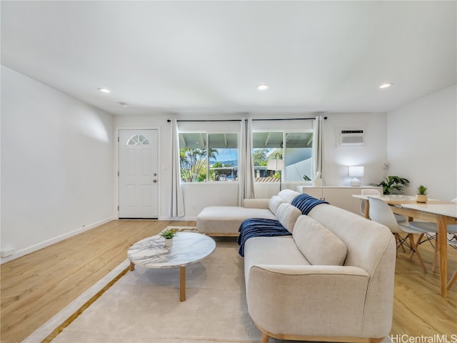 living room featuring light wood-style floors, baseboards, an AC wall unit, and recessed lighting