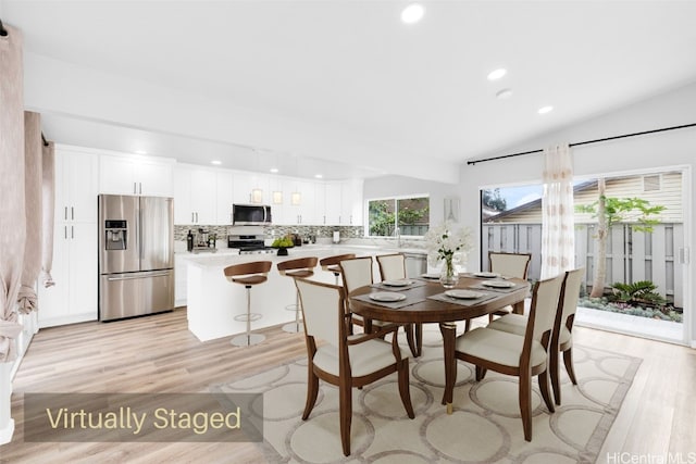 dining space featuring lofted ceiling and light hardwood / wood-style floors