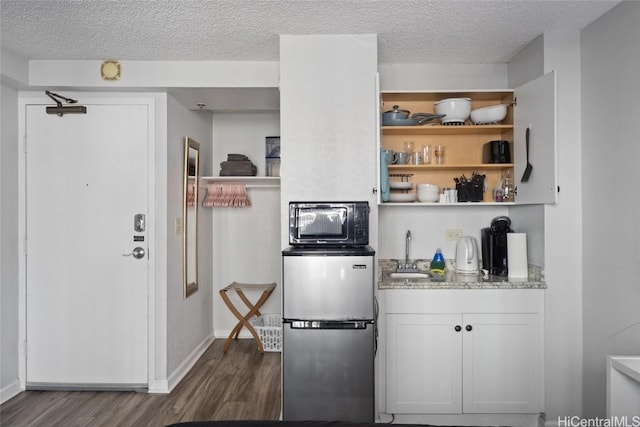 kitchen with stainless steel refrigerator, white cabinetry, sink, dark hardwood / wood-style floors, and a textured ceiling