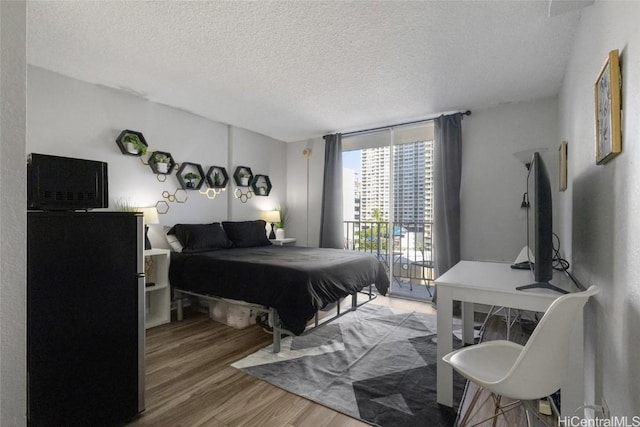 bedroom with expansive windows, wood-type flooring, and a textured ceiling