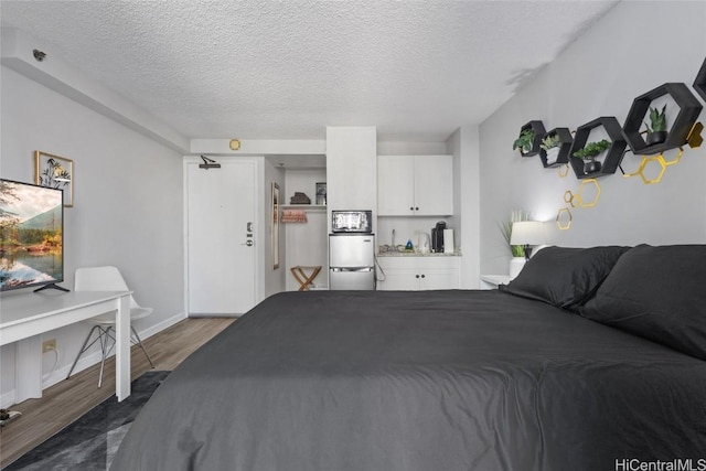 bedroom with a textured ceiling, stainless steel refrigerator, and dark wood-type flooring