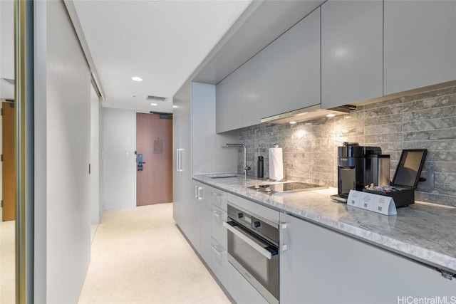 kitchen featuring stainless steel oven, light stone counters, extractor fan, black electric cooktop, and decorative backsplash