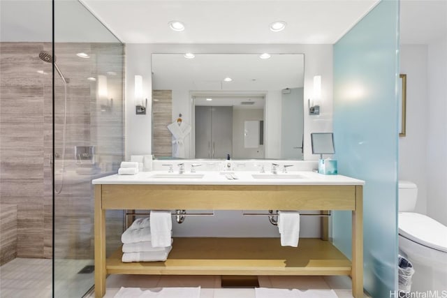 bathroom with tiled shower, tile patterned flooring, toilet, and sink