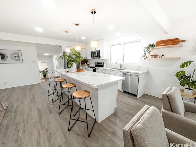 kitchen featuring appliances with stainless steel finishes, sink, pendant lighting, light hardwood / wood-style flooring, and white cabinets