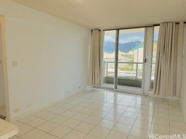 tiled empty room featuring a wall of windows