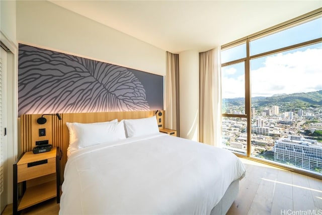 bedroom with access to exterior, wood-type flooring, and floor to ceiling windows