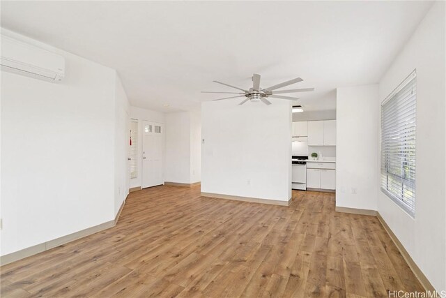 unfurnished living room with ceiling fan, light wood-type flooring, and a wall unit AC