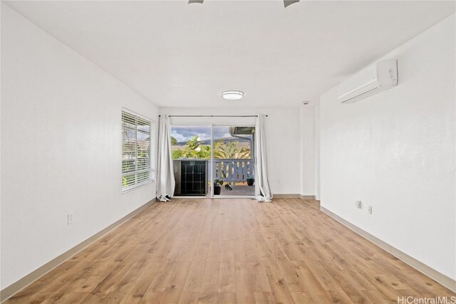 spare room with a wall unit AC and light hardwood / wood-style floors