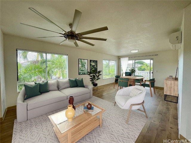 living room featuring a wall unit AC, ceiling fan, and light hardwood / wood-style floors