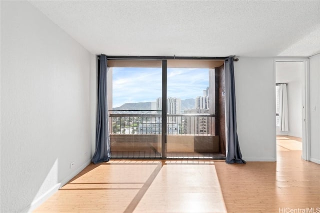 empty room featuring a wall of windows, a textured ceiling, and light hardwood / wood-style flooring