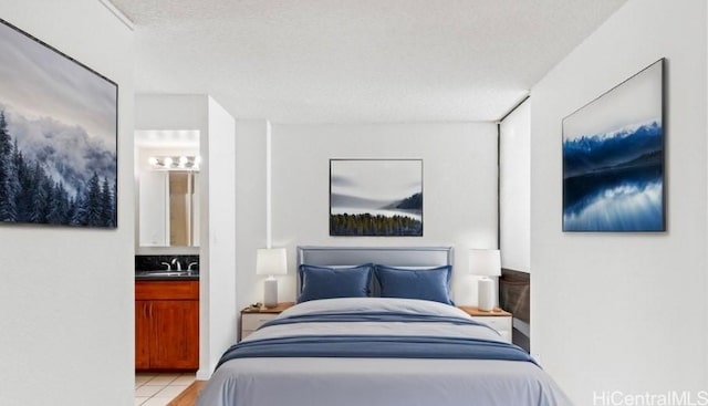 bedroom featuring sink, a textured ceiling, light tile patterned floors, and connected bathroom