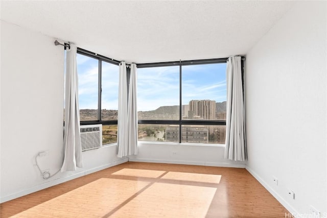 unfurnished room featuring wood-type flooring, cooling unit, and a textured ceiling