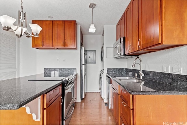 kitchen with dark stone countertops, sink, hanging light fixtures, and appliances with stainless steel finishes