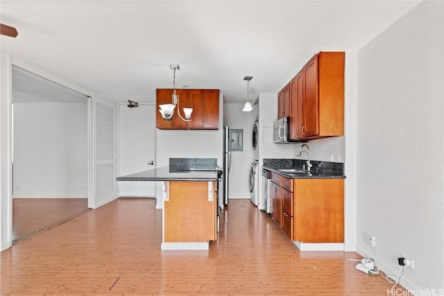 kitchen with sink, light hardwood / wood-style flooring, a breakfast bar area, hanging light fixtures, and stacked washer / drying machine