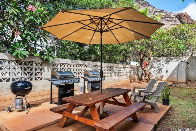 view of patio with a mountain view, a shed, and area for grilling