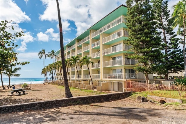 view of building exterior featuring a water view and a beach view