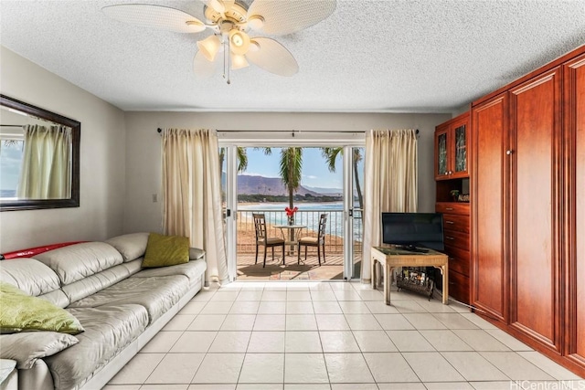 living room featuring a textured ceiling, ceiling fan, and light tile patterned flooring