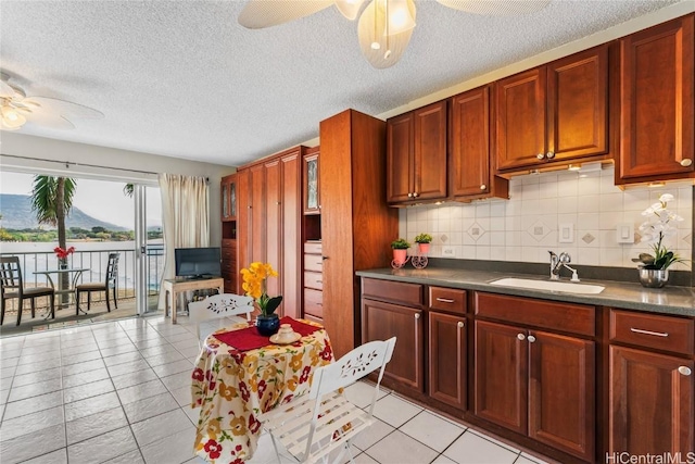 kitchen with sink, decorative backsplash, ceiling fan, light tile patterned floors, and a textured ceiling