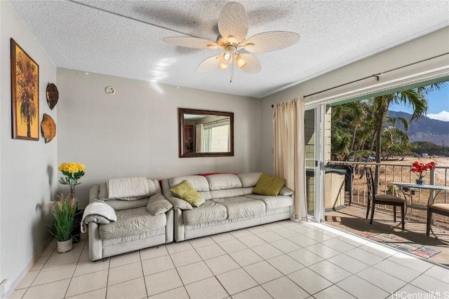 living room with ceiling fan, light tile patterned flooring, and a textured ceiling