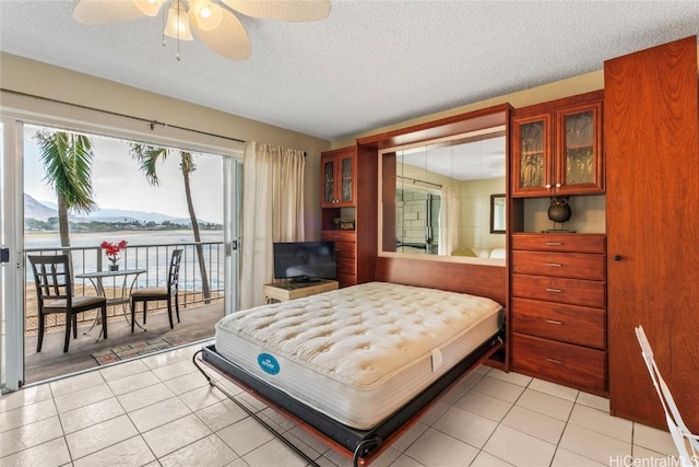 bedroom with ceiling fan, light tile patterned floors, a textured ceiling, and access to outside