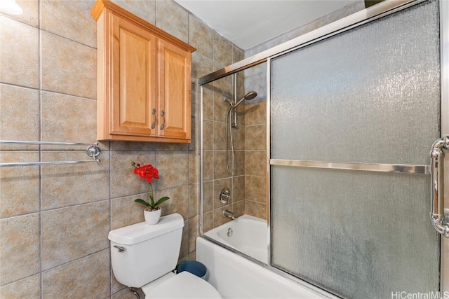 bathroom featuring toilet, tile walls, and enclosed tub / shower combo