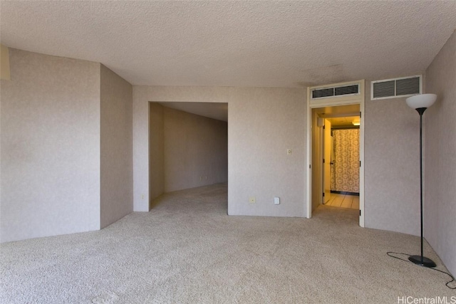 carpeted empty room featuring a textured ceiling