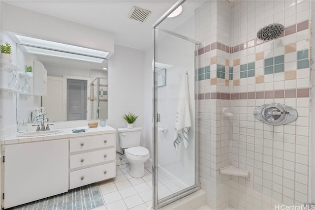 bathroom featuring tile patterned flooring, a skylight, vanity, toilet, and walk in shower