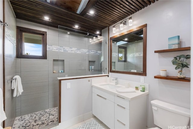 bathroom featuring tiled shower, vanity, and toilet