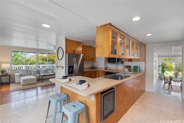 kitchen featuring light tile patterned floors, a breakfast bar, stainless steel appliances, wine cooler, and kitchen peninsula