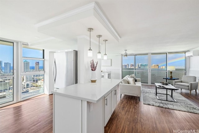 kitchen with stainless steel refrigerator, white cabinetry, ceiling fan, a wall of windows, and pendant lighting