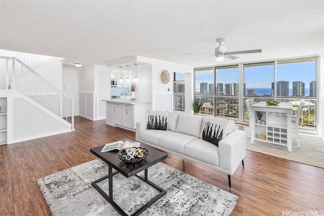 living room featuring hardwood / wood-style flooring, ceiling fan, and a wall of windows