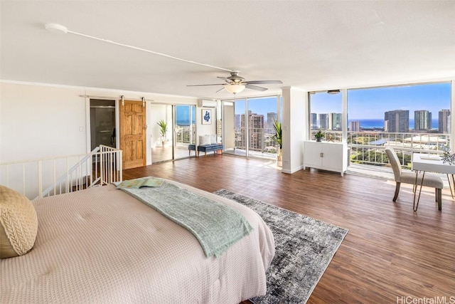 bedroom with access to exterior, ceiling fan, a barn door, expansive windows, and dark hardwood / wood-style floors