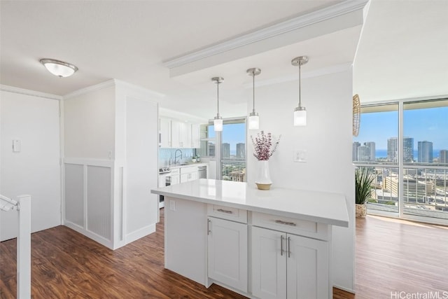 kitchen featuring tasteful backsplash, ornamental molding, white cabinets, dark hardwood / wood-style floors, and hanging light fixtures