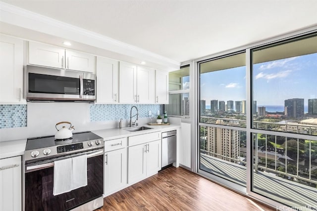 kitchen featuring dark wood-type flooring, sink, appliances with stainless steel finishes, tasteful backsplash, and white cabinetry