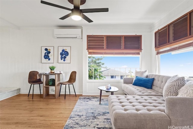 living room with ceiling fan, an AC wall unit, ornamental molding, and light hardwood / wood-style flooring