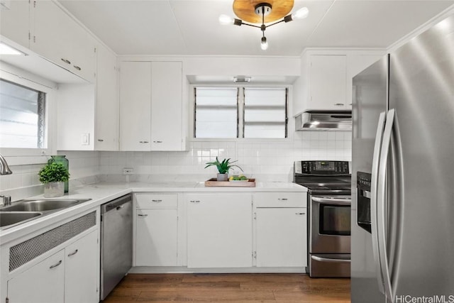 kitchen featuring tasteful backsplash, white cabinetry, wall chimney range hood, and appliances with stainless steel finishes