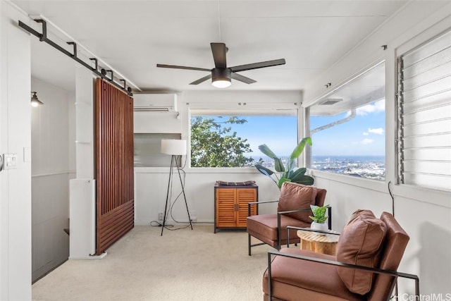 sitting room featuring ceiling fan, a barn door, an AC wall unit, and a wealth of natural light