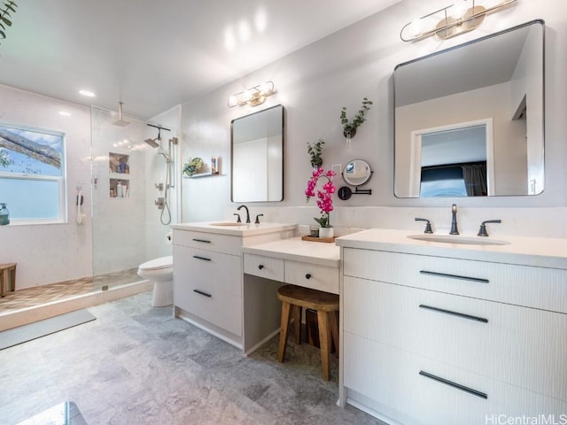 bathroom with toilet, tiled shower, and vanity