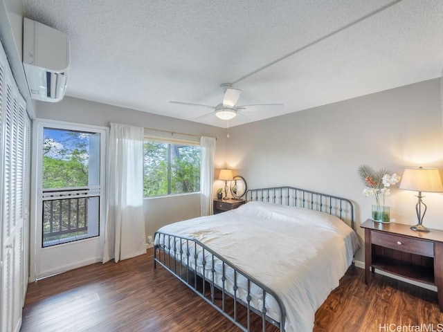 bedroom with dark wood-type flooring, a textured ceiling, a wall unit AC, and ceiling fan