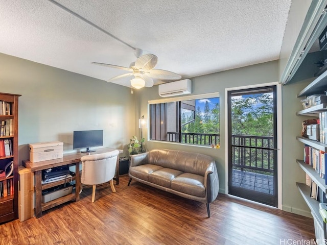 living room with a textured ceiling, ceiling fan, a wall unit AC, and hardwood / wood-style flooring