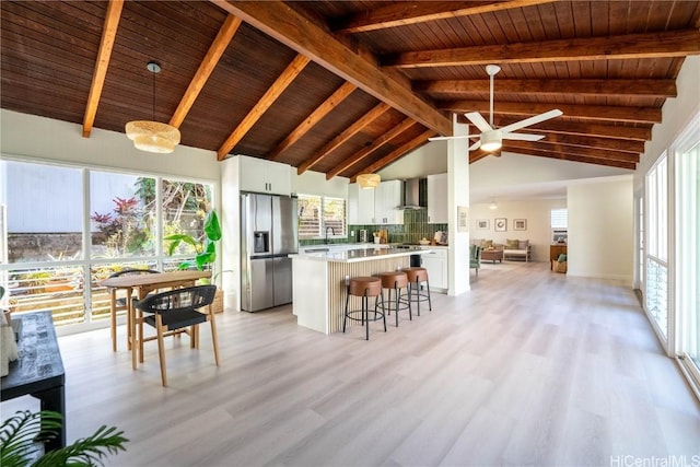 kitchen with pendant lighting, wall chimney range hood, stainless steel refrigerator with ice dispenser, white cabinetry, and wood ceiling