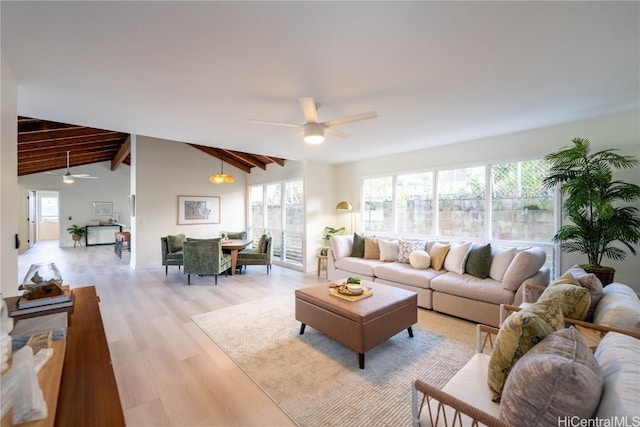 living room with ceiling fan, a healthy amount of sunlight, light hardwood / wood-style floors, and lofted ceiling with beams